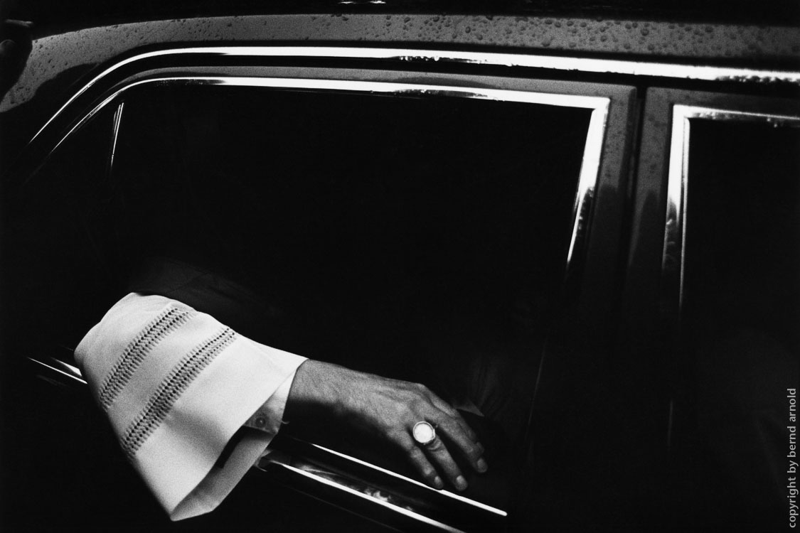 Arcbishop in his car with open window and his arm outside in Cologne. Cologne salvation